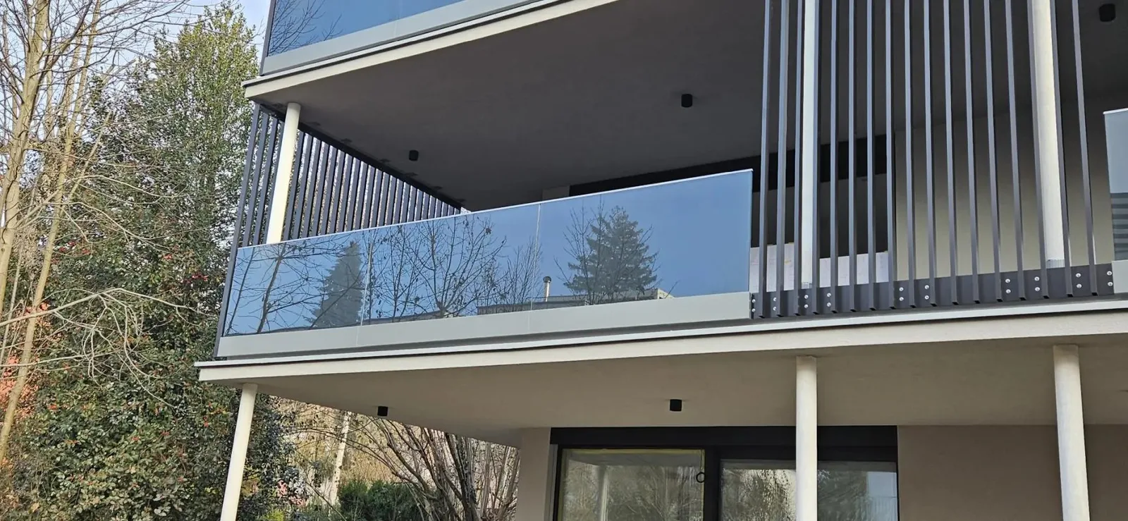 Balkon mit Glasgeländer und vertikalen Metalllamellen